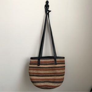 Unbranded neutral colour market bag in natural material with leather straps.
